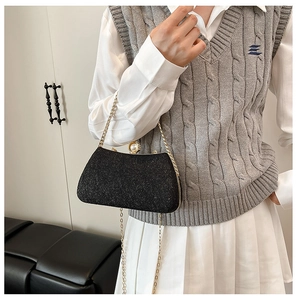 Detail of black glitter evening bag with gold frame, chain and pearl clasp closure
