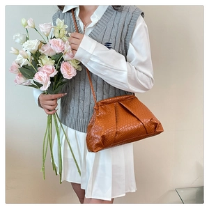 Close-up of caramel woven dumpling bag with ruched closure and leather shoulder strap