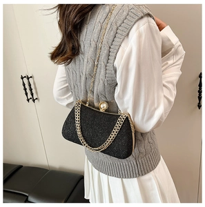 Detail of black glitter crossbody bag with gold chain and oversized faux pearl clasp