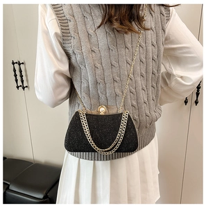 Detail of black glitter clutch with pearl clasp and decorative gold chain straps