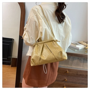 Detail of gold woven texture and knot handle on a stylish crossbody cloud bag