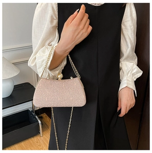 Detailed close-up of sparkling sequined clutch bag with pearl clasp and gold chain strap