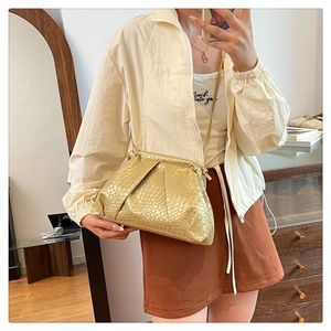 Macro shot of metallic gold textured leather handbag with sleek crossbody strap