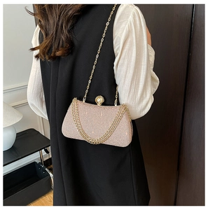 Detail of pink gold glitter clutch bag featuring pearl clasp and elegant gold chain strap