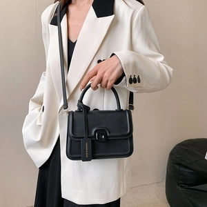 Chic black matte crossbody bag with square buckle shown in a stylish commute setting