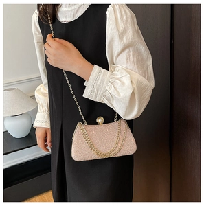 Detail of the pink glitter handbag featuring a large pearl clasp and fine gold chain strap