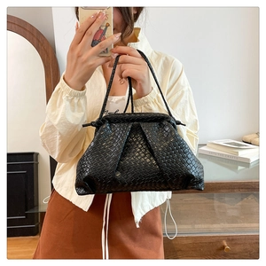 Close-up of black woven leather texture and elegant pleats on the shell-shaped bag