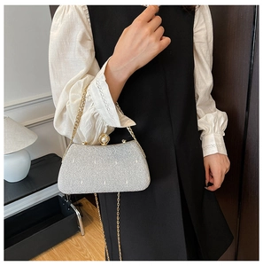 Detail of silver glitter clutch bag featuring a large pearl clasp and gold chain strap