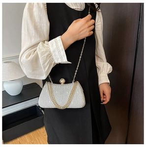 Detail of silver sequin evening clutch with pearl clasp and golden chain strap