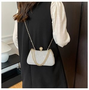 Detail of silver glitter clutch bag with pearl gold clasp and slim metal chain