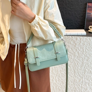 Retro light green crossbody bag with woven texture flap and metallic buckles on beige coat