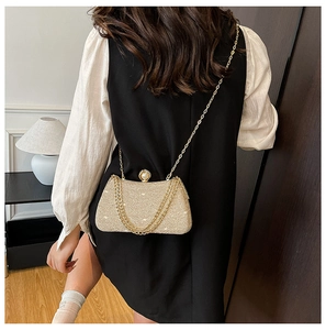 Detail of champagne gold glitter evening bag with pearl clasp and chain strap on model