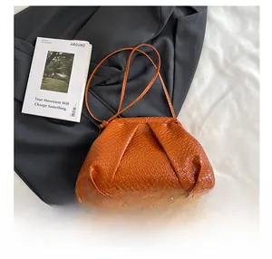 Detailed close-up of brown woven cloud bag with leather strap and pleated texture