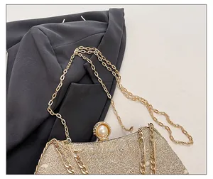 Detail of champagne gold lace clutch with pearl clasp and elegant metal chain strap