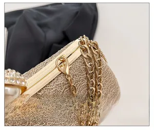 Close-up of gold evening clutch with lace texture, luxury pearl and rhinestone clasp detail