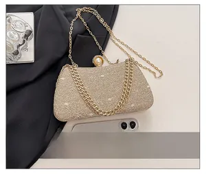 Detail view of gold sequin evening clutch featuring large pearl clasp and chain strap