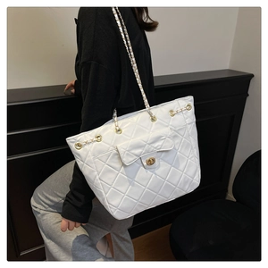 Détail d'un sac cabas matelassé blanc avec fermoir doré et bandoulière en chaîne métal