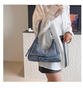 Détail du sac hobo en jean bleu avec triples sangles à boucle métallique sur l'épaule