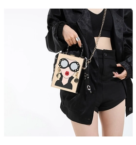 Détail du sac boîte doré chic avec portrait de femme en dessin animé et chaîne en métal