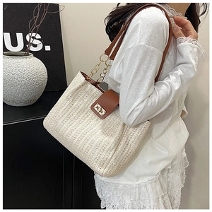 Close-up of handmade woven tote bag with brown leather strap and gold metal hardware