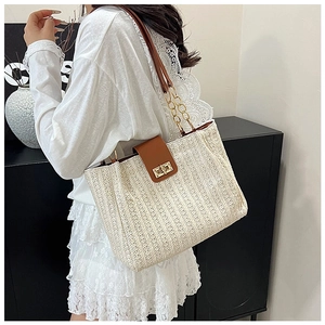 Detail of hand-woven straw tote bag featuring brown leather flap and golden metal twist lock