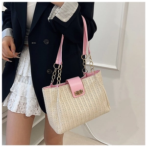 Detail of pink leather handles and metal chain on a straw tote bag with gold turn-lock