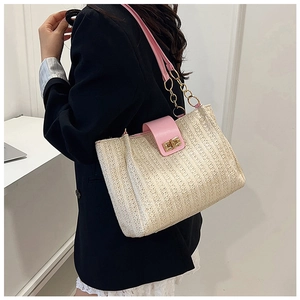 Detail of straw tote bag with pink leather trim and gold chain handle decoration