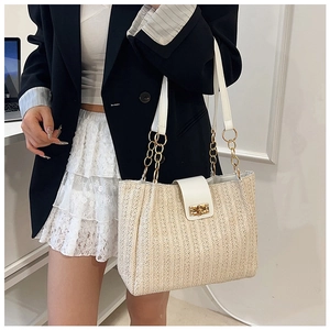 Close-up of woven straw tote bag with white leather flap and gold chain detail