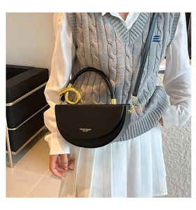 Détail d'un sac demi-lune en cuir noir avec matériel en métal doré et logo imprimé