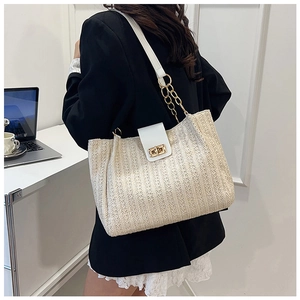 Detail of a straw tote bag with white leather flap, gold twist lock, and chain strap