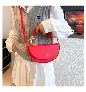 Détail du sac à main rouge demi-lune avec poignée dorée et texture en cuir