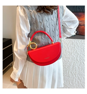 Détail du sac demi-lune en cuir rouge avec poignée ronde dorée et fine bandoulière