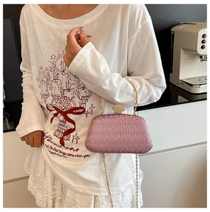 Detail of pink fabric晚宴 evening bag with diamond clasp and gold chain handle held by model