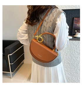 Détail d'un sac selle en cuir marron avec poignée dorée élégante et bandoulière assortie