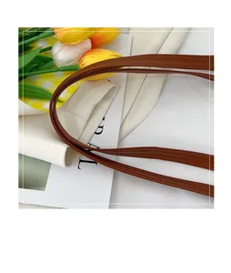 Close-up of caramel brown leather handle with fine stitching details on a woven tote bag