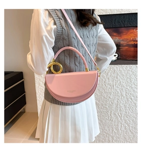 Close-up of semi-circle pink crossbody bag with gold ring handle and adjustable strap