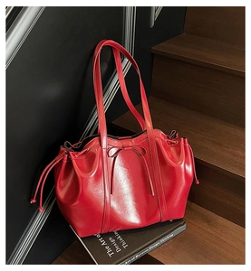 Détail du sac cabas rouge brillant avec nœud et cordon de serrage sur un escalier