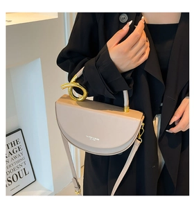 Detail of a khaki semi-circle leather bag with a gold twisted metal handle for women