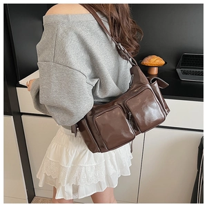 Detail of dark brown glossy shoulder bag showing side view with front zippered pockets