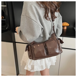Detail of dark brown glossy leather crossbody bag with multiple functional pockets