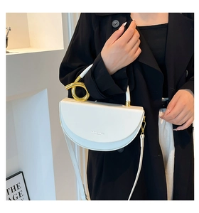 Detail of white half-moon bag featuring a unique spiral gold metal handle and logo