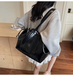 Vue détaillée de dos d'un grand sac cabas noir brillant sur un mannequin dans un salon