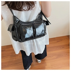Detail of a black shiny patent leather shoulder bag with multiple utility zip pockets