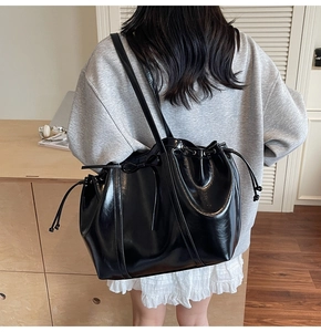Détail du sac cabas noir brillant avec fermeture à cordon et décor de nœud