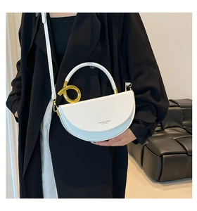 Détail du sac selle blanc montrant l'anneau doré latéral et la texture du cuir