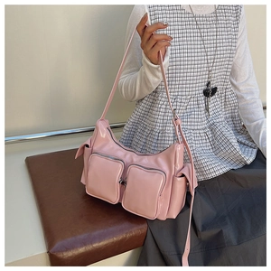 Close-up of pink patent leather shoulder bag with functional zippers and utility pockets