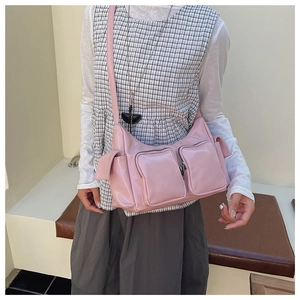 Detailed view of pink glossy underarm bag featuring multiple utility zippers and side pockets