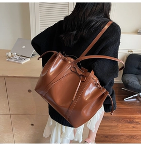Détail du sac cabas en cuir brillant marron avec un nœud décoratif en cordon coulissant
