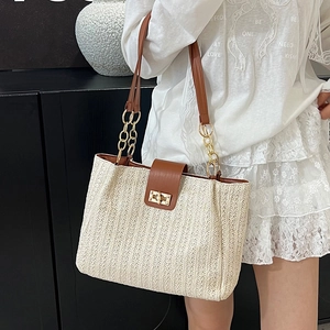 Straw woven tote bag with brown leather flap and gold chain strap on female model