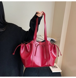 Détail d'un sac cabas rouge brillant avec cordon à nœud et fines bandoulières